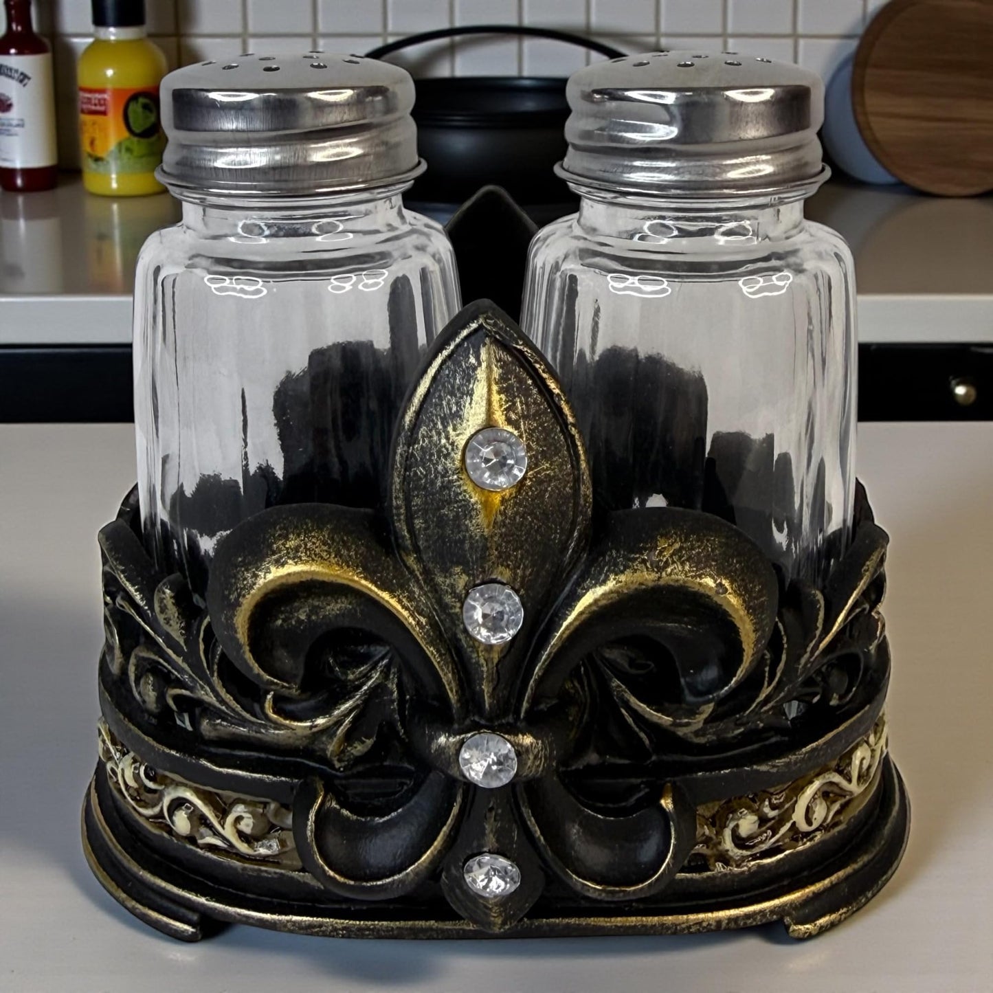 Fleur De Lis Salt and Pepper Shaker Set with Decorative Resin Holder – Glass Shakers with Stainless Steel Lids – French Country Cajun Kitchen Decor – 3 3/4” Tall Tabletop Seasoning Set